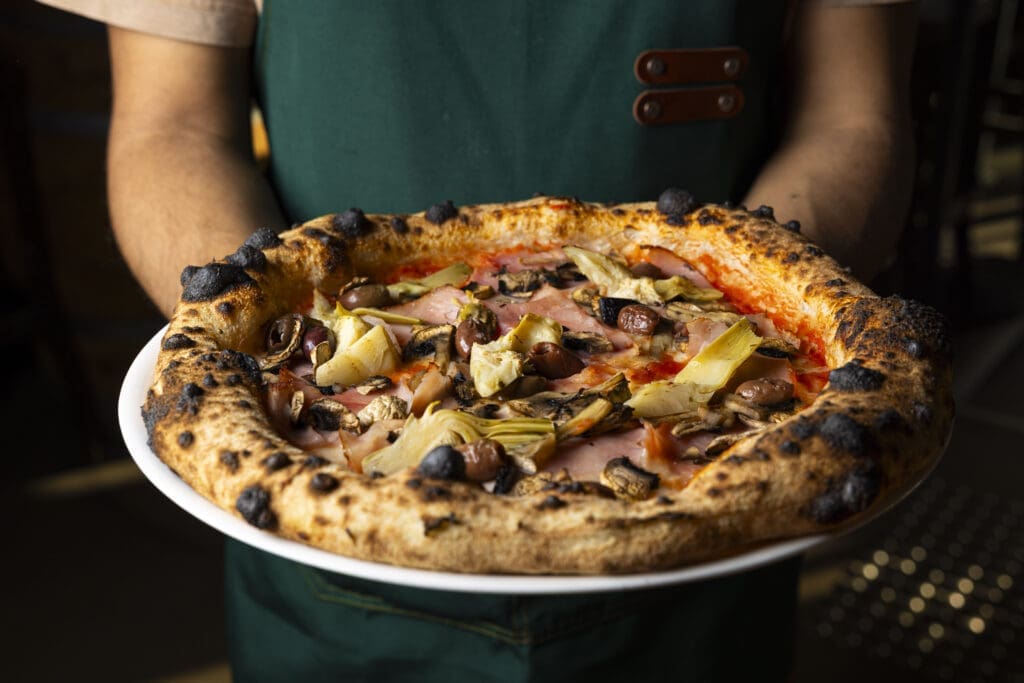 Aperitivo-Capricciosa-Pizza-Being-Held